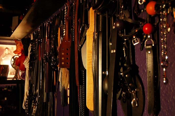 BDSM impact implements hanging on dungeon wall